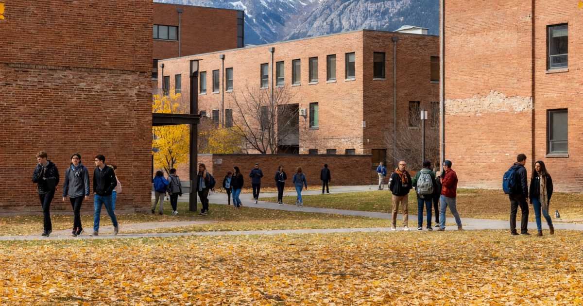 A university campus quad with brick buildings and students walking in autumn, illustrating Alberta student aid in 2026-27.