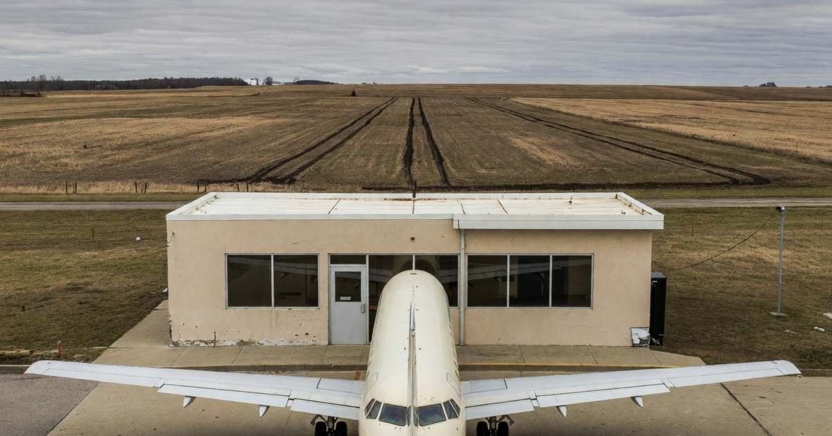 A small regional airport terminal with a single jet parked at the gate, illustrating alternate Canadian airports that cut fares.