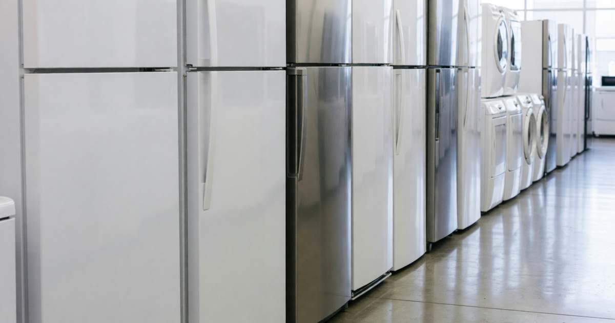 A row of new appliances in a store aisle with blank sides facing the camera, illustrating counter-tariffs and checking country of origin on appliances.