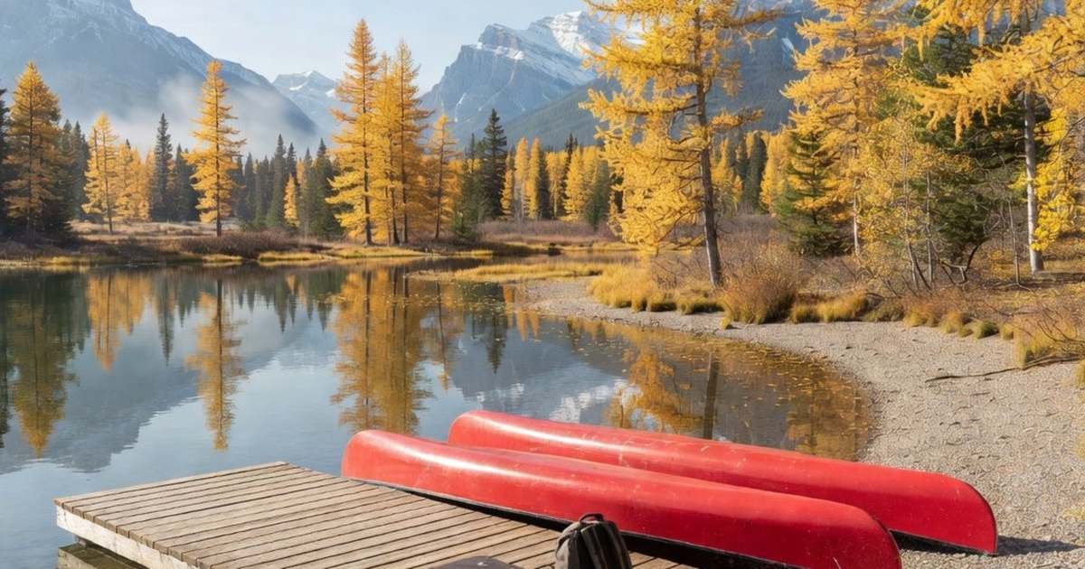 A quiet mountain lake in the Canadian Rockies in late September with canoes and a suitcase on an empty dock, illustrating the cheapest shoulder-season months to travel from Canada.