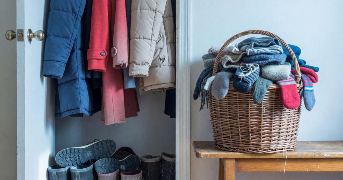 A family's front hall closet with winter coats, boots and a basket of hats and mitts, illustrating how much a Canadian household should spend on clothing.