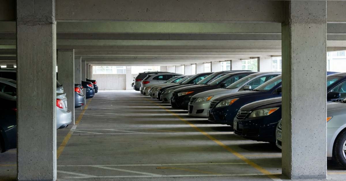 A row of parked cars in an underground condo parking garage, illustrating how condo parking costs change car ownership math.