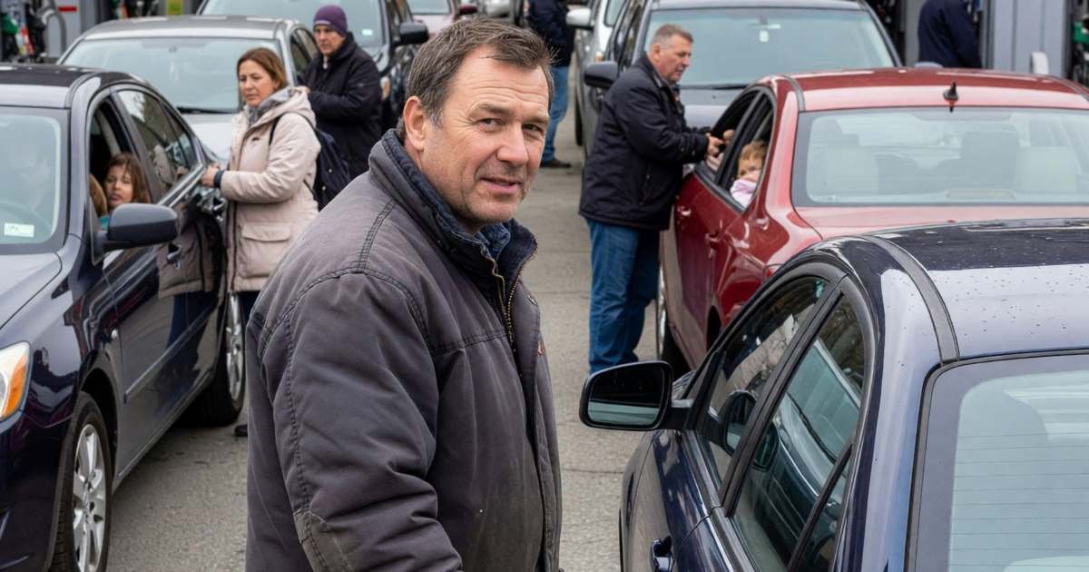 A man filling up his car at a busy warehouse-club gas bar with long queues of cars, illustrating whether Costco gas makes the membership worth it in Canada.