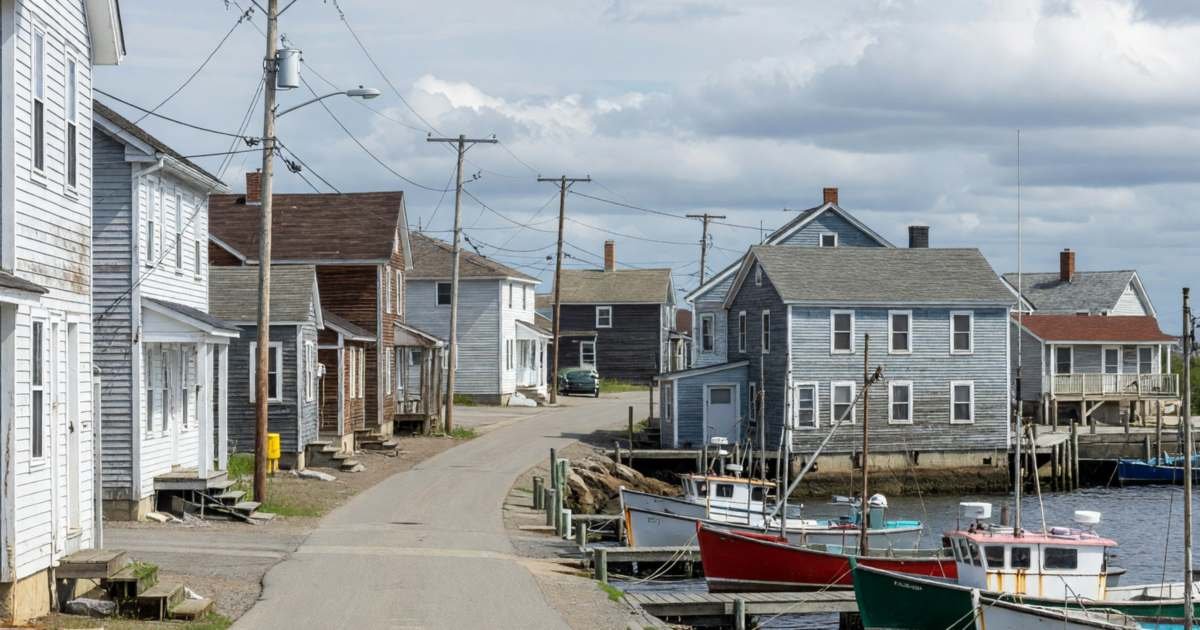 A small fishing village with wooden houses and utility poles along a coastal road, illustrating comparing Eastlink internet deals in Atlantic Canada.