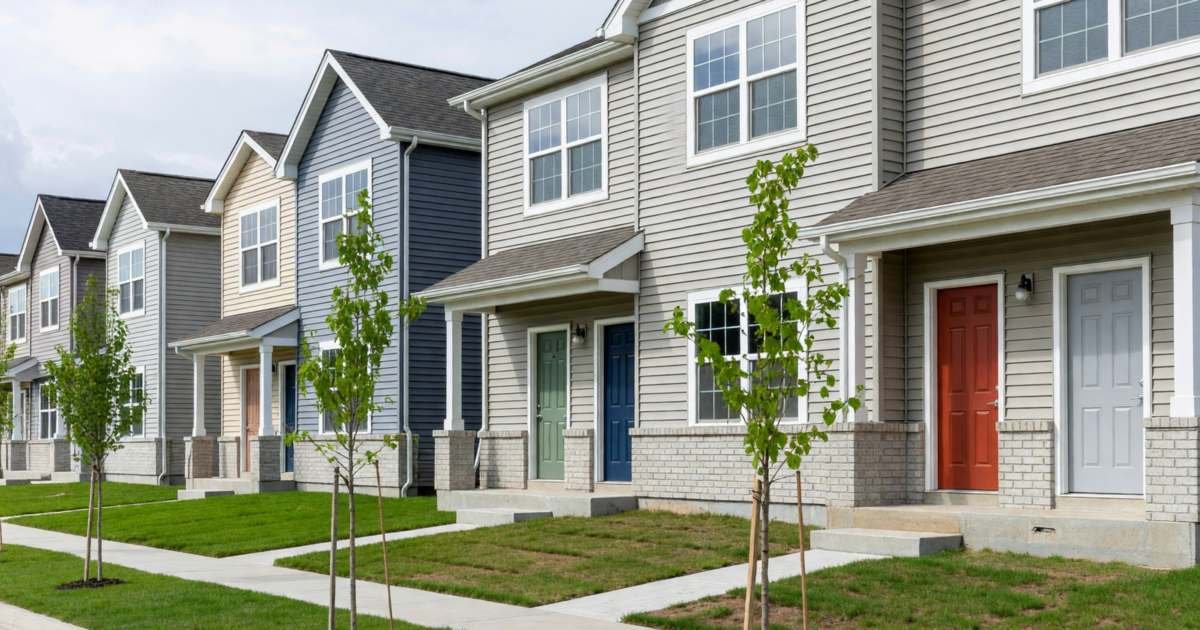 A quiet new-build townhouse street with small saplings and fresh sod, illustrating options for Canadian first-time buyers after the FTHBI closed.