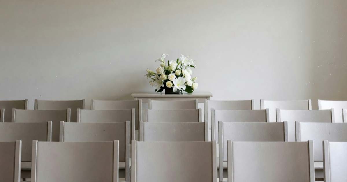 A funeral home chapel with rows of chairs and a simple flower arrangement, illustrating funeral costs and the CPP death benefit.