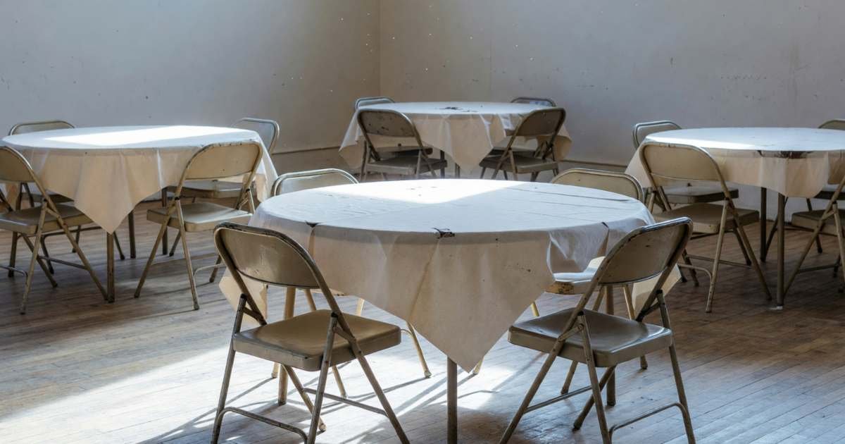 An empty community hall set up for a party with round tables and folding chairs, illustrating renting a hall for a party.