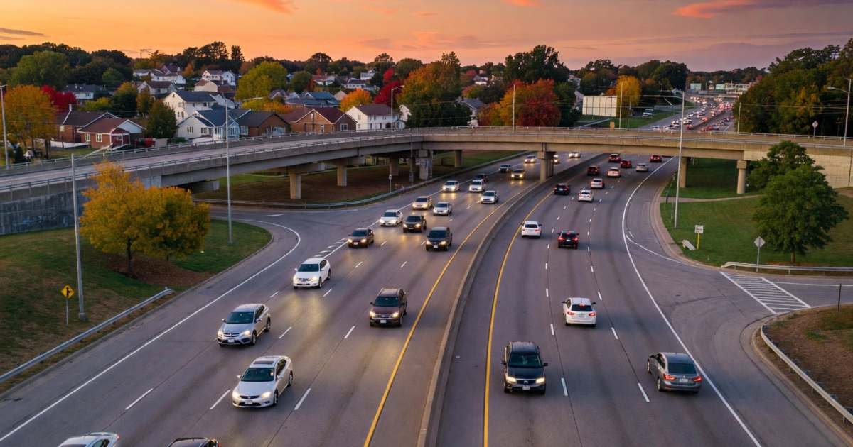 A wide multi-lane highway curving through suburbs with light traffic at dusk, illustrating deciding when Highway 407 tolls are worth it.
