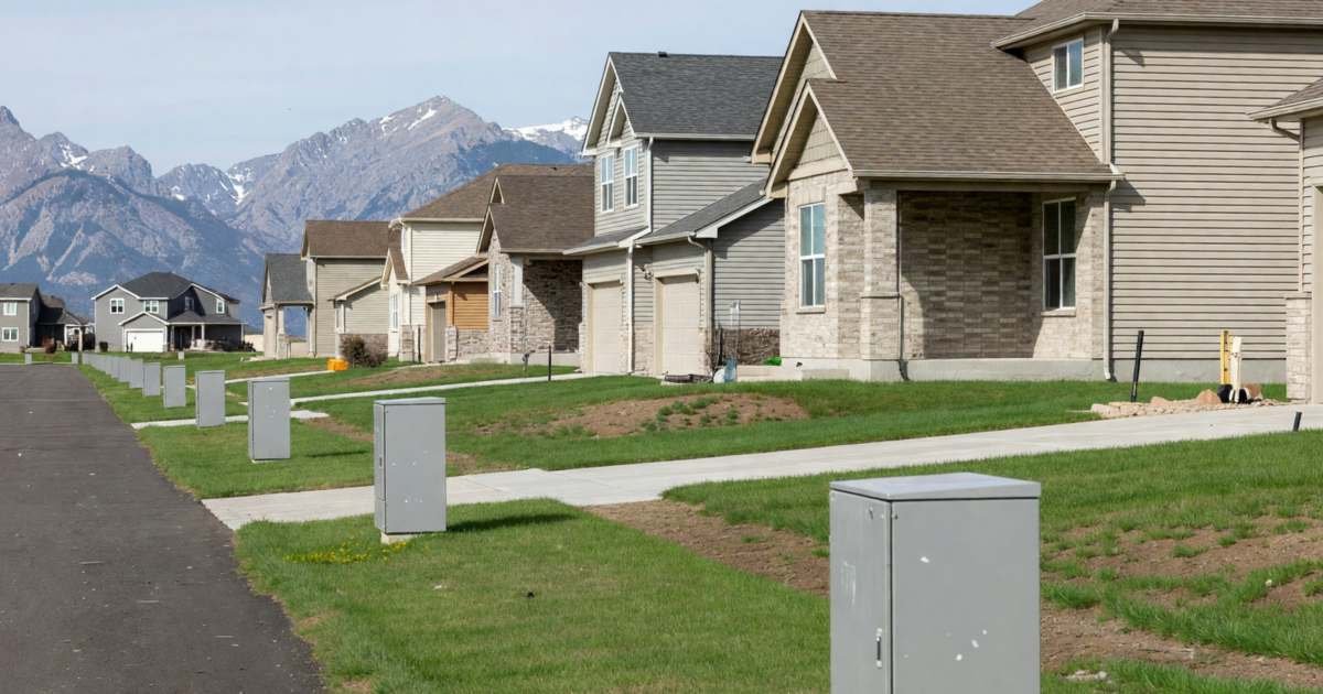 A suburban street of new homes with fibre utility boxes along the boulevard, illustrating home internet in Calgary and Edmonton.