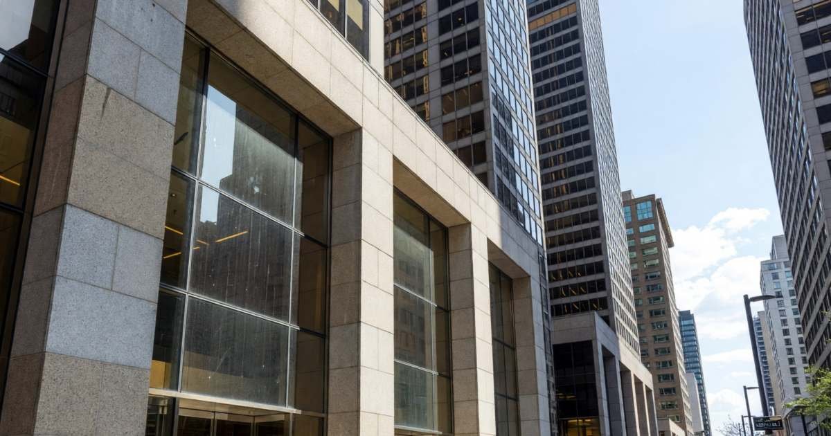 The stone and glass entrances of big bank towers on a downtown financial-district street, illustrating leaving a Big-5 bank fee package in Canada.
