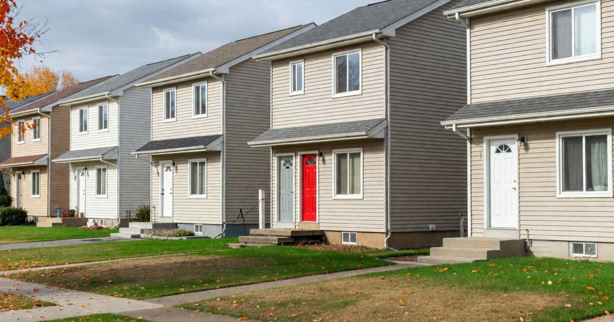 A row of similar suburban houses seen from across the street, one with a bright red door, illustrating reviewing and challenging a property assessment in Canada.