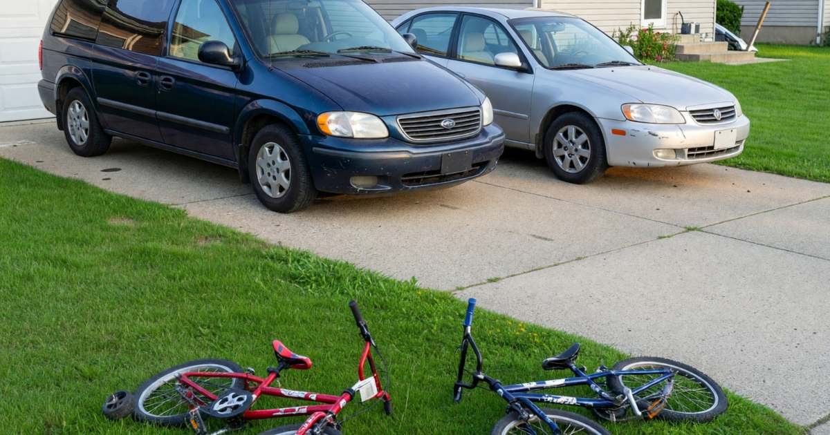 Two cars, a minivan and a small sedan, parked in a family driveway in front of a house, illustrating multi-car insurance discounts in Canada.
