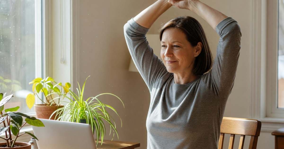 A woman in a home office on a video break, stretching by the window with a mug, illustrating negotiating hybrid work to cut commuting costs.