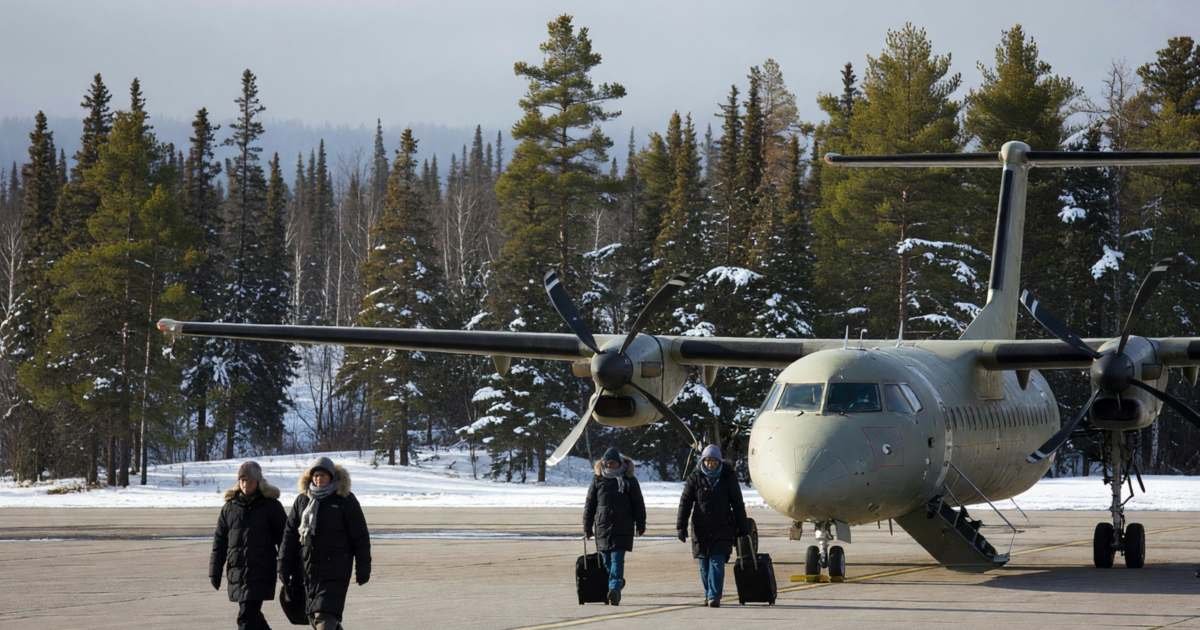 A small regional airport with a turboprop plane on the tarmac and boreal forest beyond, illustrating Ontario's Northern Health Travel Grant.