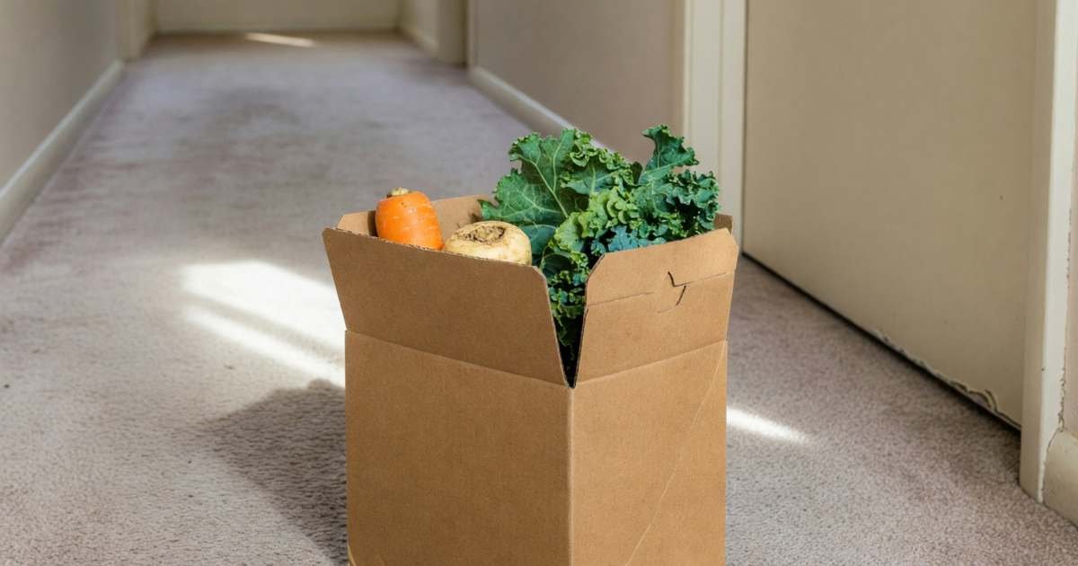 A meal-kit box left on an apartment doorstep with a few vegetables peeking out, illustrating skipping or cancelling HelloFresh before the weekly deadline.