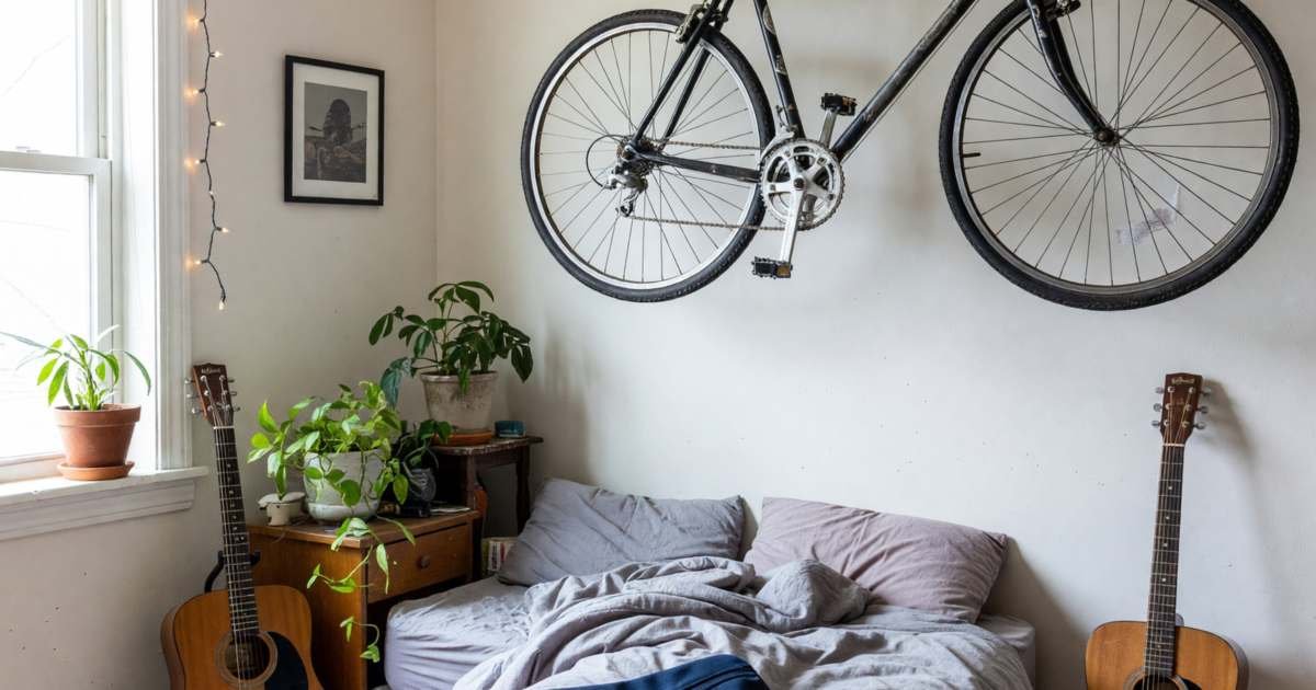 A young renter's bedroom with a bike on a wall rack, a laptop bag on the bed and a guitar in the corner, illustrating tenant insurance coverage for renters in Canada.