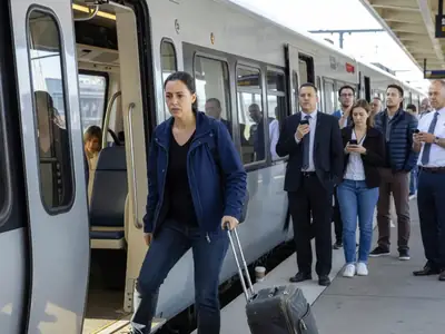 A woman with a suitcase boarding an airport express train.