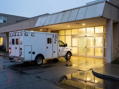 An ambulance parked at a hospital emergency entrance at dusk.