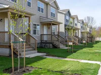 A row of new townhouses with small front porches and young trees.