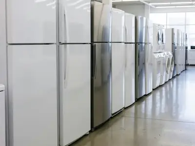 A row of new appliances in a store aisle with blank sides facing the camera.