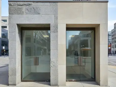 Two different bank branch entrances side by side on a downtown street corner, glass doors and stone facades.