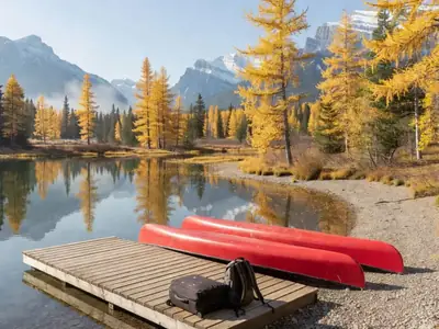 A quiet mountain lake in the Canadian Rockies in late September with canoes and a suitcase on an empty dock.