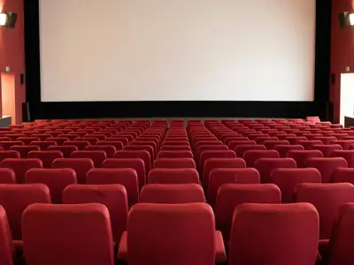 Rows of empty red cinema seats facing a blank screen.