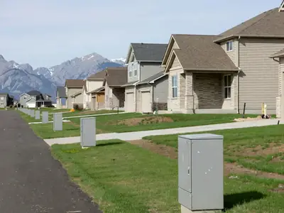 A suburban street of new homes with fibre utility boxes along the boulevard.