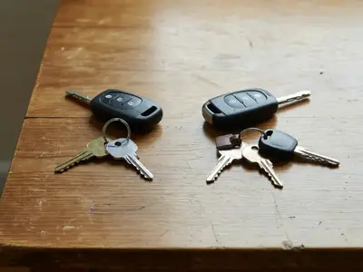Two sets of keys and two car fobs on a table, one pushed to each side.