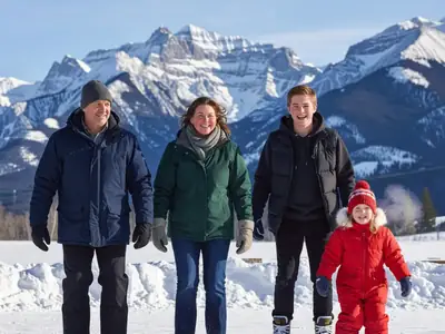 A family skating on an outdoor rink with mountains behind during a winter break.