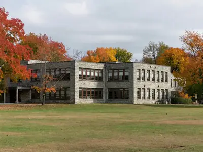 A private school building with a stone façade and an empty playing field.
