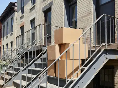 Exterior metal staircases of a row of Montréal walk-up apartments with moving boxes stacked on a landing.