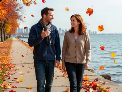 A couple in their thirties walking along a waterfront path, deep in friendly conversation about plans.