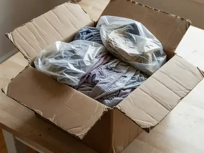 A cheap overseas parcel opened on a table showing thin, poorly sewn clothes in plastic bags.