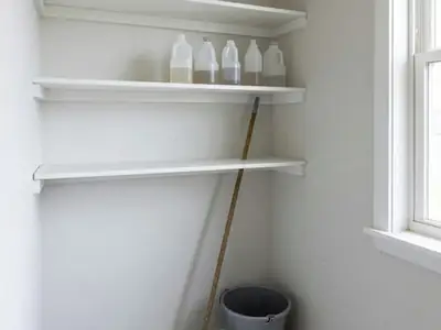 A small tidy cleaning closet with a few refill bottles, a mop and a bucket.