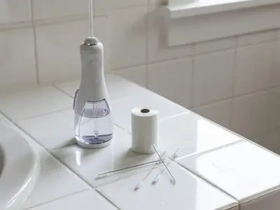 A water flosser, a roll of floss and a few interdental brushes on a bathroom counter.