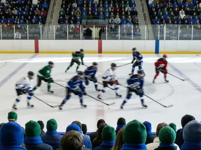 An arena full of fans in winter colours during a junior hockey game.