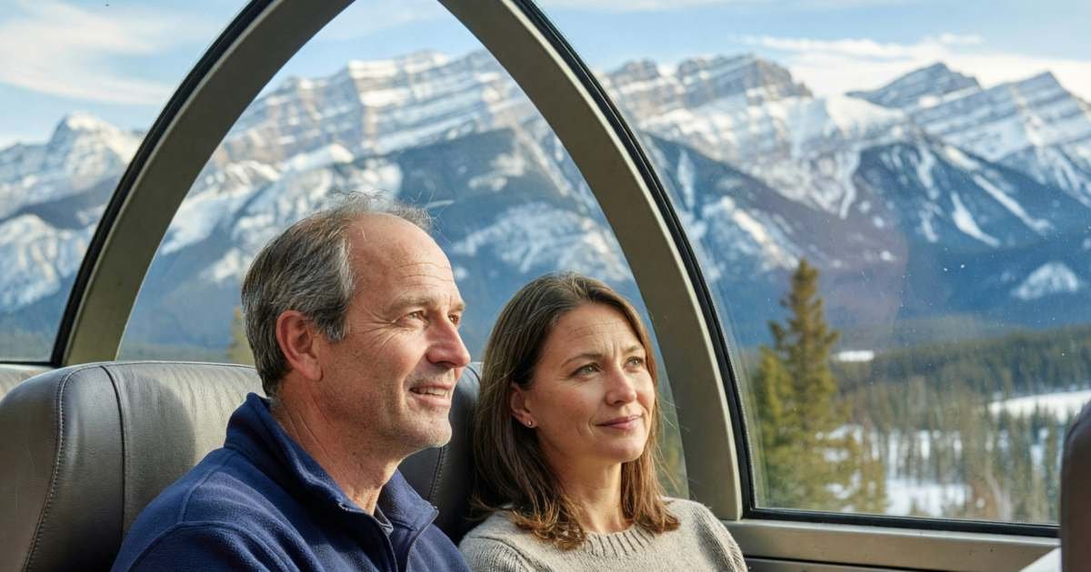 A couple in a train's dome car watching the Rockies roll by, illustrating VIA Rail for leisure trips in Canada.