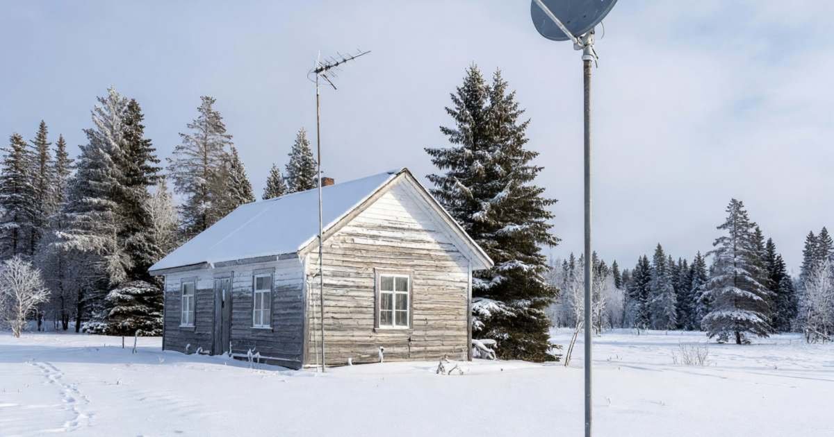 A rural property in winter with a satellite dish on a pole and a fixed wireless antenna on the house, illustrating Xplore versus Starlink for rural Canada.